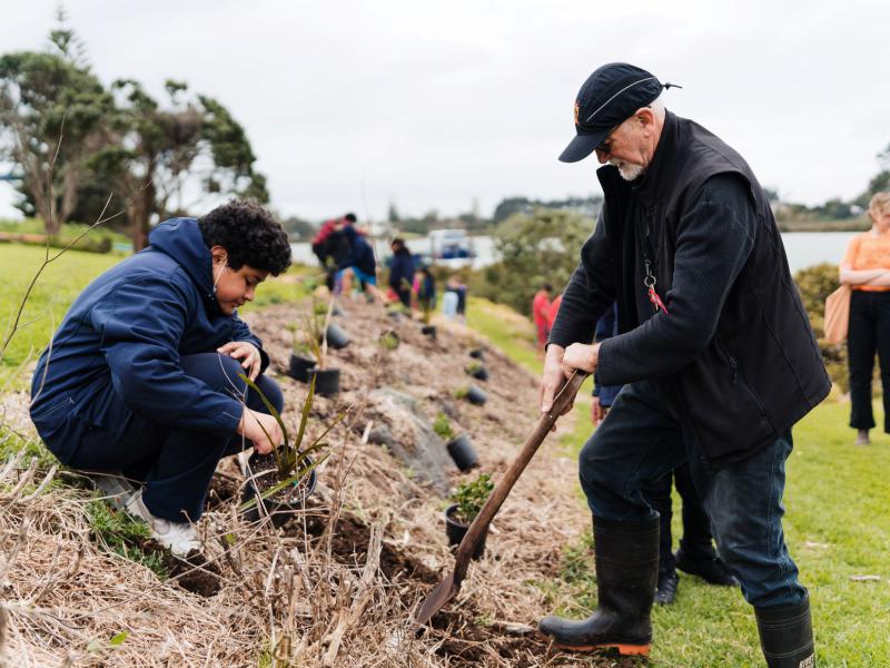 Boy and older man planting native trees